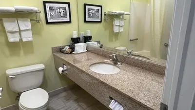 a bathroom with a sink and a toilet and a mirror at Super 8 by Wyndham Albany in Albany