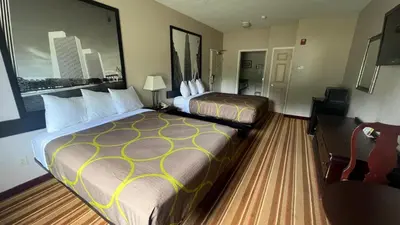 a hotel room with two beds and a chair at Super 8 by Wyndham Albany in Albany