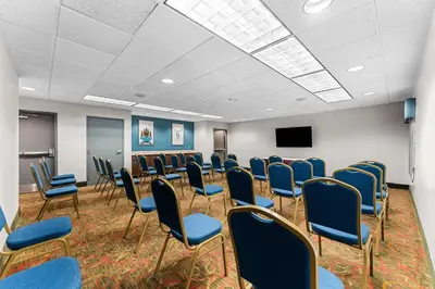 a conference room with blue chairs and a screen at Hampton Inn Stroudsburg Poconos in Stroudsburg