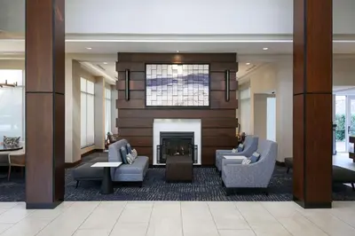 a lobby with two chairs and a fireplace at Hilton Garden Inn Melville in Plainview
