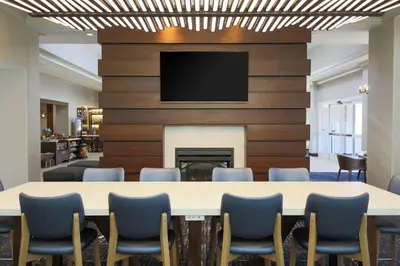 a conference room with a table and chairs and a fireplace at Hilton Garden Inn Melville in Plainview