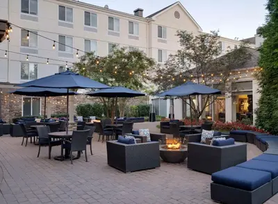 an outdoor patio with tables and chairs and umbrellas at Hilton Garden Inn Melville in Plainview