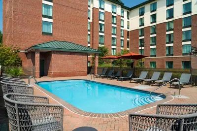 a pool in front of a hotel with chairs and umbrellas at Homewood Suites by Hilton Hartford South-Glastonbury in Glastonbury