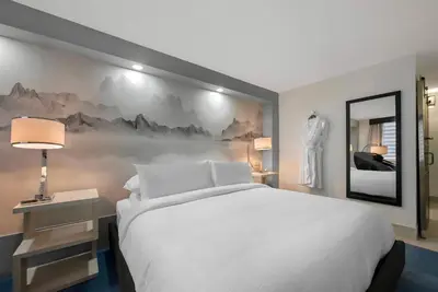 a bedroom with a white bed and a wall with mountains at Blue - A Modern Hotel, an Ascend Collection Hotel in West Springfield