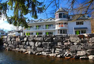 a building behind a stone wall next to the water at The Roxbury in Roxbury