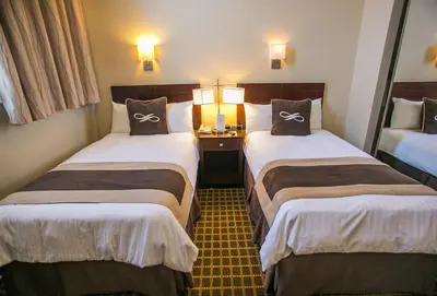 a hotel room with two beds and two lamps at Pointe Plaza Hotel in Brooklyn