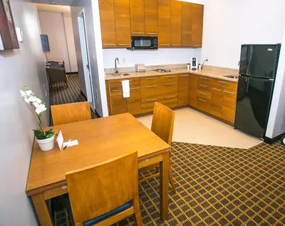 a kitchen with a wooden table and a refrigerator at Pointe Plaza Hotel in Brooklyn