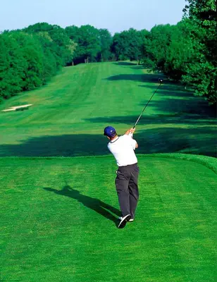 a man swinging a golf club on a golf course at Hilton Garden Inn Nanuet in Nanuet