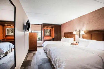 a hotel room with two beds and a mirror at Hampton Inn West Springfield in West Springfield