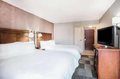 a hotel room with two beds and a flat screen tv at Hampton Inn West Springfield in West Springfield