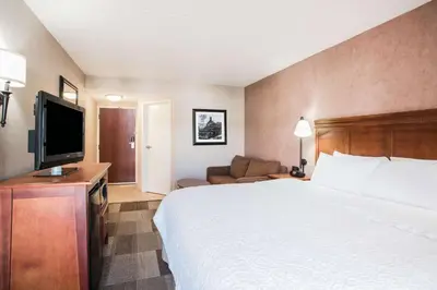 a hotel room with a bed and a flat screen tv at Hampton Inn West Springfield in West Springfield