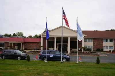 two flags in a parking lot in front of a building at Rodeway Inn & Suites East Windsor in East Windsor