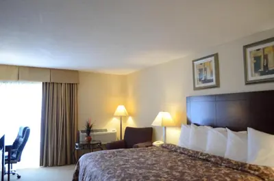 a hotel room with a bed and a chair and a window at Rodeway Inn & Suites East Windsor in East Windsor