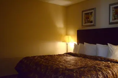a hotel room with a large bed with a lamp at Rodeway Inn & Suites East Windsor in East Windsor