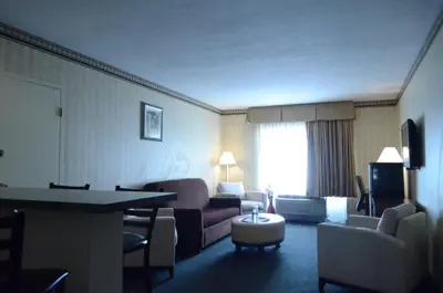 a hotel room with a living room with a couch and chairs at Rodeway Inn & Suites East Windsor in East Windsor