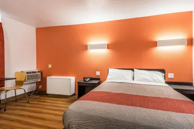 a hotel room with a bed with an orange wall at Motel 6-Schenectady, NY in Schenectady