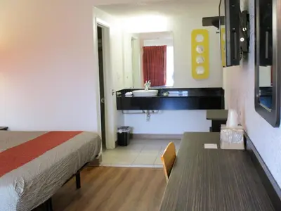 a room with a bed and a bathroom with a sink at Motel 6-Schenectady, NY in Schenectady