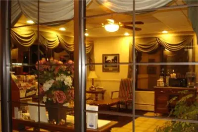 a reflection of a room with a flower arrangement in a window at Colonie Inn and Suites in Latham