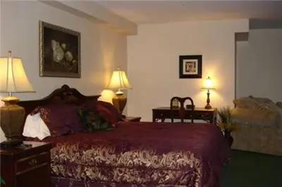 a bedroom with a bed and two lamps and a chair at Colonie Inn and Suites in Latham