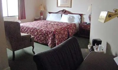 a hotel room with a bed and a chair at Colonie Inn and Suites in Latham
