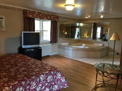 a hotel room with a tub and a bed and a television at Colonie Inn and Suites in Latham
