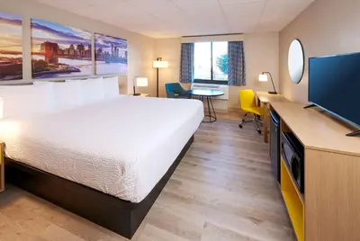 a hotel room with a bed and a flat screen tv at Days Inn by Wyndham Parsippany in Parsippany