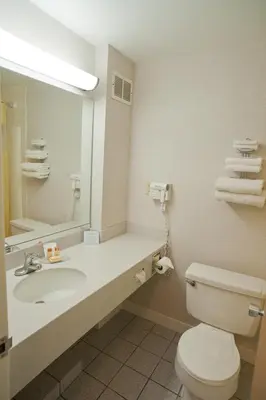 a bathroom with a sink and a toilet and a mirror at Days Inn by Wyndham Parsippany in Parsippany