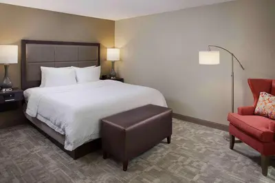 a hotel room with a bed and a red chair at Hampton Inn by Hilton Garden City Long Island in Garden City