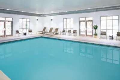 a large swimming pool in a room with windows at Hampton Inn by Hilton Garden City Long Island in Garden City