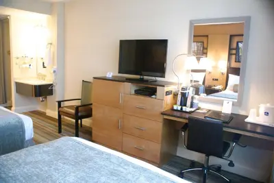 a hotel room with a bed and a desk with a television at Best Western Queens Gold Coast in Queens
