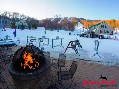 a fire pit with chairs and a playground in the snow at Jiminy Peak Mountain Resort in Hancock