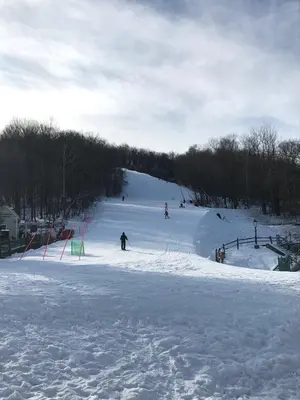 a group of people skiing down a snow covered slope at Jiminy Peak Mountain Resort in Hancock