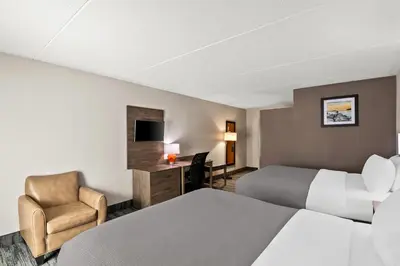 a hotel room with two beds and a chair at Quality Inn Westfield - Springfield in Westfield