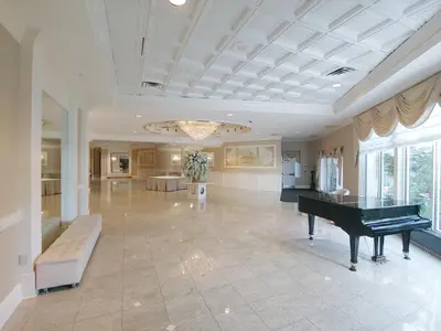 a large living room with a piano and a table at The Wilshire Grand Hotel in West Orange
