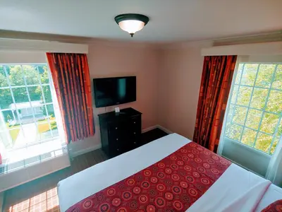 a bedroom with a bed and a flat screen tv at The Wilshire Grand Hotel in West Orange