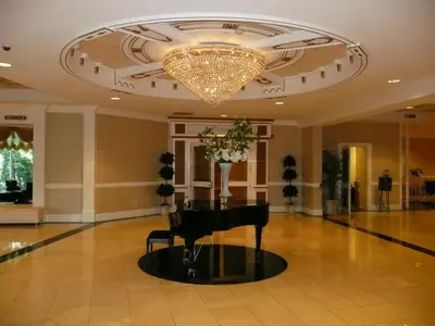 a grand piano in a lobby with a chandelier at The Wilshire Grand Hotel in West Orange