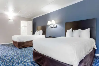 two beds in a hotel room with blue walls at Econo Lodge Hicksville - Long Island in Hicksville
