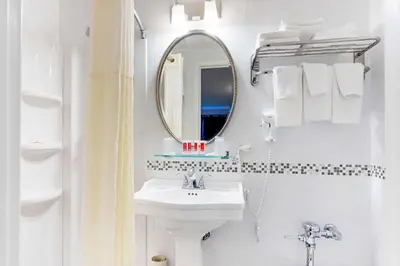 a white bathroom with a sink and a mirror at Econo Lodge Hicksville - Long Island in Hicksville