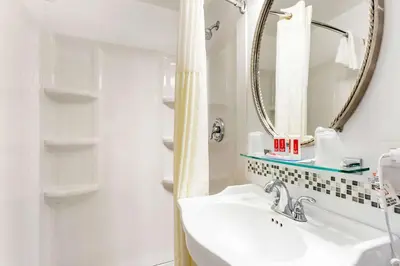 a white bathroom with a sink and a mirror at Econo Lodge Hicksville - Long Island in Hicksville