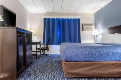 a hotel room with a bed and a flat screen tv at Econo Lodge Hicksville - Long Island in Hicksville