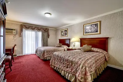 a hotel room with two beds and a window at Roosevelt Inn & Suites Saratoga Springs in Saratoga Springs
