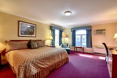 a hotel room with a bed and a chair at Roosevelt Inn & Suites Saratoga Springs in Saratoga Springs