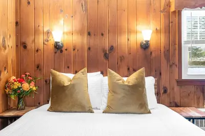 a bedroom with a bed with pillows and a vase of flowers at Phoenicia Lodge in Phoenicia