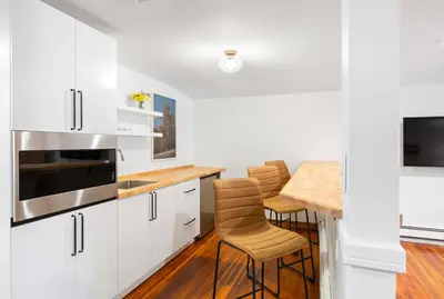a kitchen with white cabinets and a table with stools at Phoenicia Lodge in Phoenicia