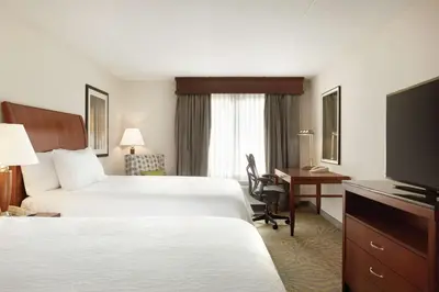 a hotel room with two beds and a desk and a television at Hilton Garden Inn Shelton in Shelton