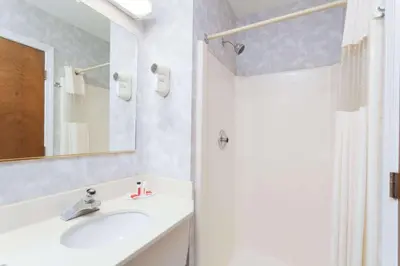 a white bathroom with a sink and a shower at Travelodge by Wyndham Great Barrington Berkshires in Great Barrington