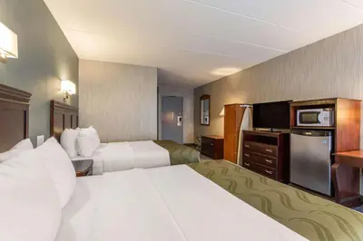a hotel room with two beds and a flat screen tv at Quality Inn West Springfield in West Springfield