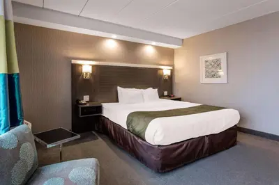 a hotel room with a large bed and a chair at Quality Inn West Springfield in West Springfield