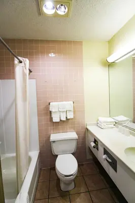 a bathroom with a toilet and a tub and a sink at FairBridge Inn and Suites West Point in Highland Falls