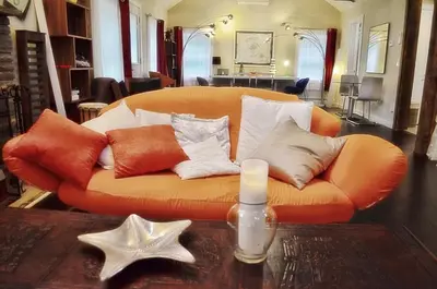 an orange couch with pillows and a candle on a table at Romantic, Magical Cottage in Catskills nr Woodstock in Willow
